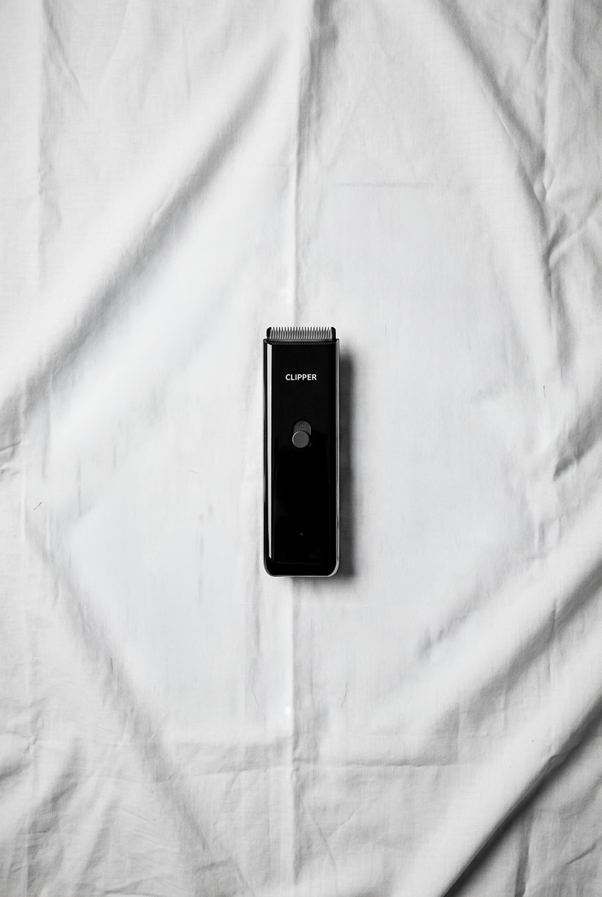 Black hair clipper on a white fabric background