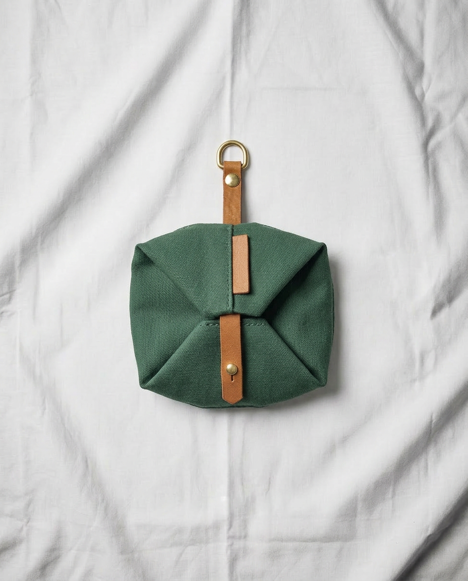 Green fabric pouch with leather strap on a white background